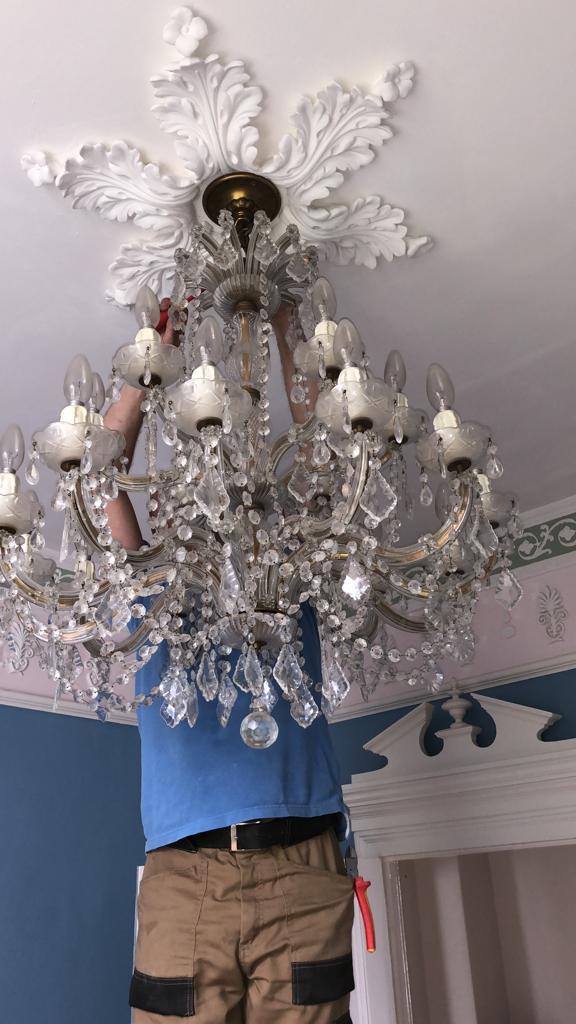 Ornate chandelier installation in Brighton period property